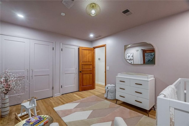 bedroom featuring light wood-type flooring and a nursery area