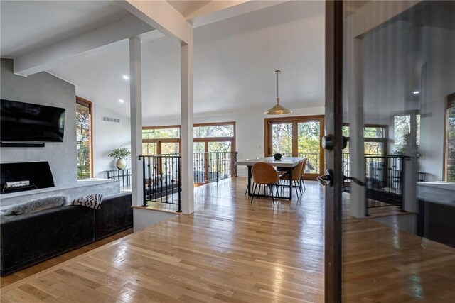 living room featuring a large fireplace, lofted ceiling with beams, a healthy amount of sunlight, and wood-type flooring