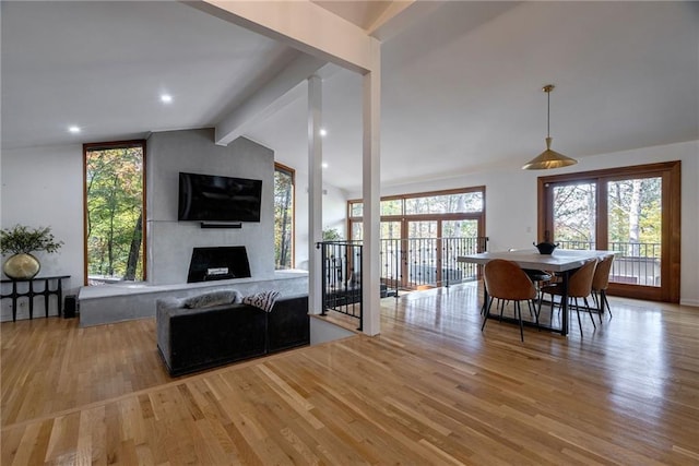 interior space featuring lofted ceiling with beams, a large fireplace, light hardwood / wood-style flooring, and a healthy amount of sunlight