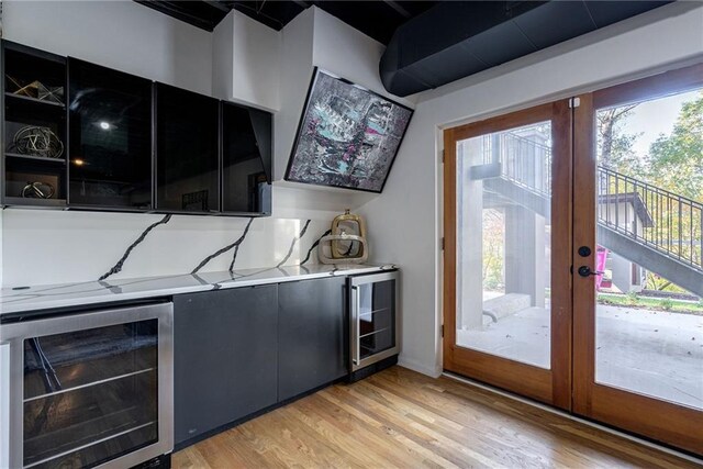 kitchen featuring a healthy amount of sunlight, light wood-type flooring, beverage cooler, and french doors