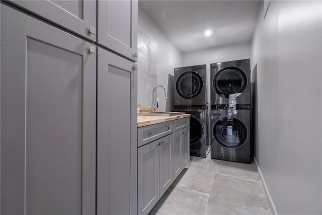 laundry room with cabinets, stacked washer and clothes dryer, and sink