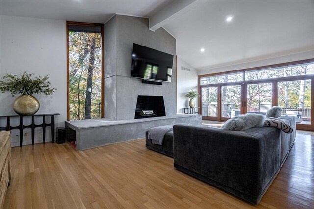 living room featuring lofted ceiling with beams, wood-type flooring, and a fireplace