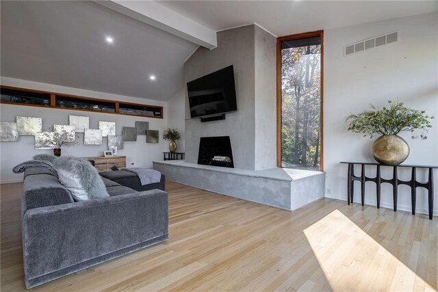 living room featuring vaulted ceiling with beams and light wood-type flooring