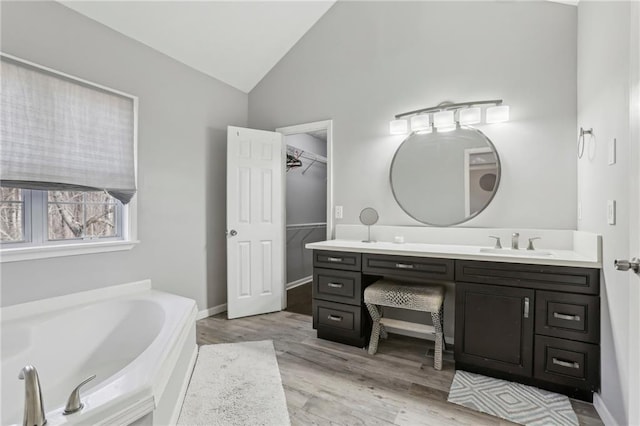 bathroom featuring a tub to relax in, hardwood / wood-style floors, vanity, and vaulted ceiling