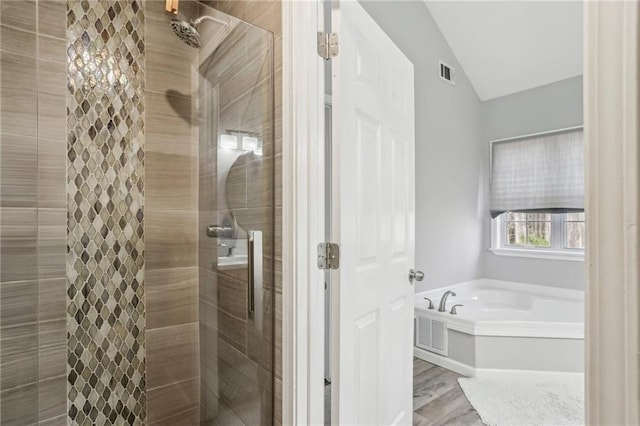 bathroom with wood-type flooring, separate shower and tub, and vaulted ceiling