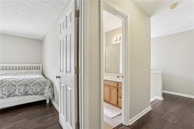 bedroom with ensuite bathroom, dark hardwood / wood-style flooring, and sink