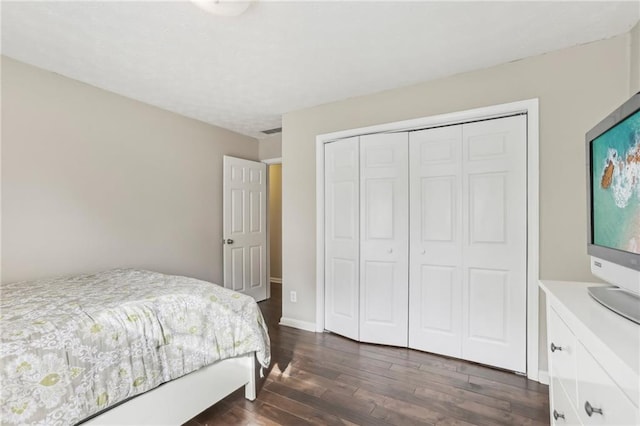 bedroom with dark hardwood / wood-style flooring and a closet