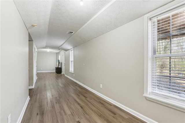 corridor with wood-type flooring and a textured ceiling