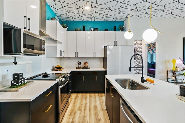 kitchen featuring white cabinetry, sink, stainless steel appliances, tasteful backsplash, and decorative light fixtures