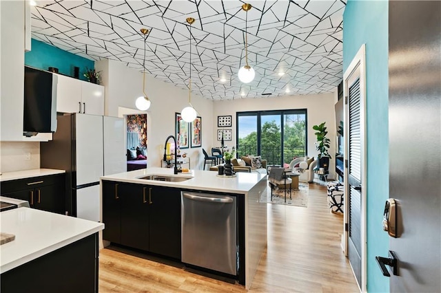 kitchen featuring sink, dishwasher, white cabinetry, hanging light fixtures, and an island with sink