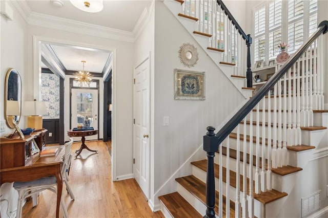 5807 Peacock Ln, Hoschton, GA 30548 - entryway with visible vents, baseboards, light wood-type flooring, ornamental molding, and an inviting chandelier