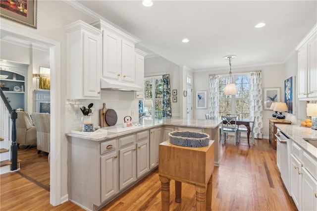 5807 Peacock Ln, Hoschton, GA 30548 - kitchen with under cabinet range hood, a peninsula, crown molding, and white cabinetry
