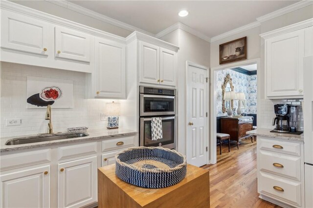 5807 Peacock Ln, Hoschton, GA 30548 - kitchen with ornamental molding, a sink, white cabinetry, light wood-style floors, and double oven