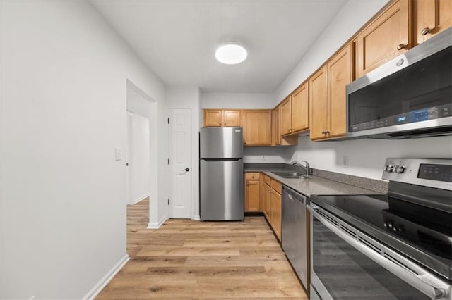 kitchen featuring appliances with stainless steel finishes, sink, and light wood-type flooring