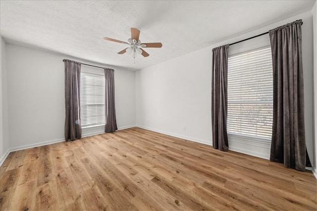 empty room with ceiling fan, a textured ceiling, and light wood-type flooring