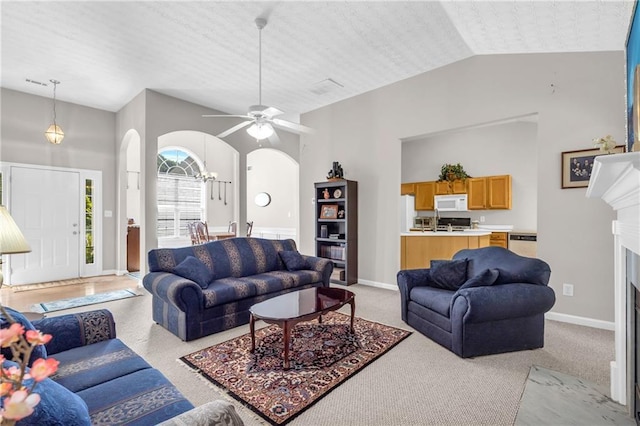 1530 Brisbane Dr, Dacula, GA 30019 - living area featuring arched walkways, a ceiling fan, light carpet, a fireplace, and high vaulted ceiling