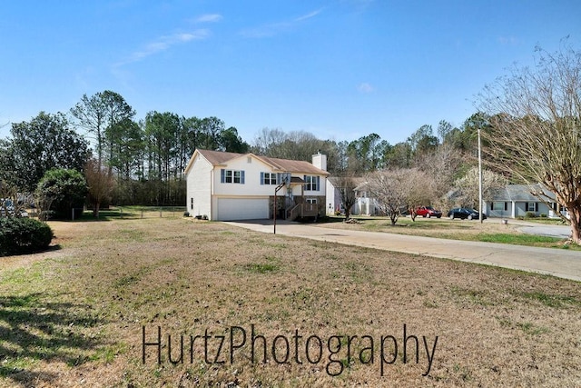 exterior space featuring a garage, a front yard, a chimney, and driveway