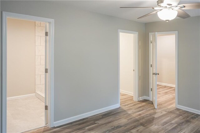 unfurnished bedroom with ceiling fan, wood-type flooring, and ensuite bath