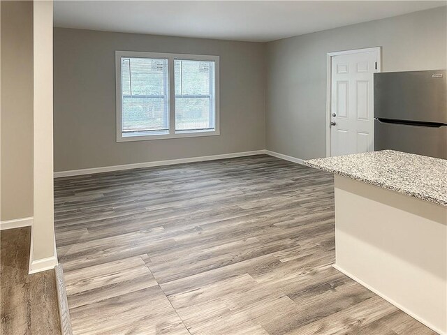 interior space featuring light stone counters, light wood-type flooring, and stainless steel refrigerator