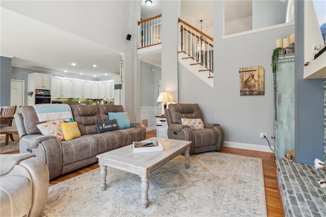 living room featuring stairs, recessed lighting, baseboards, a high ceiling, and wood finished floors