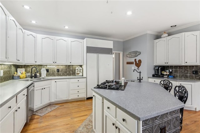 kitchen featuring light wood finished floors, ornamental molding, a sink, and dishwasher