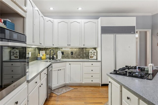 kitchen with white cabinetry, crown molding, light wood-style floors, and a sink