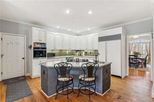 kitchen with stainless steel microwave, white cabinets, a sink, and oven