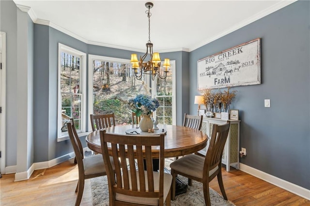 dining space with baseboards, wood finished floors, ornamental molding, and an inviting chandelier