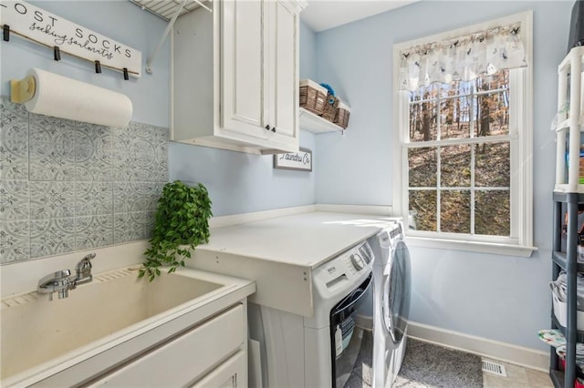 clothes washing area with a sink, light tile patterned floors, baseboards, washer and dryer, and cabinet space