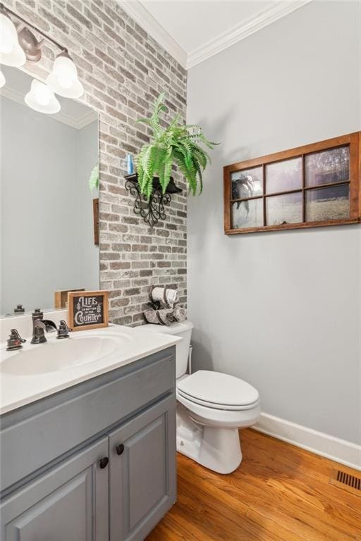 bathroom with vanity, crown molding, toilet, baseboards, and wood finished floors