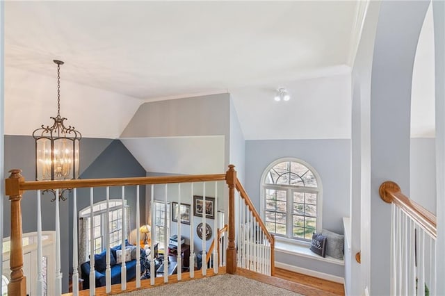 stairway featuring baseboards, lofted ceiling, and a chandelier