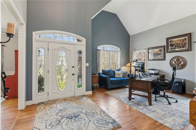entrance foyer featuring light wood-style flooring, high vaulted ceiling, and baseboards