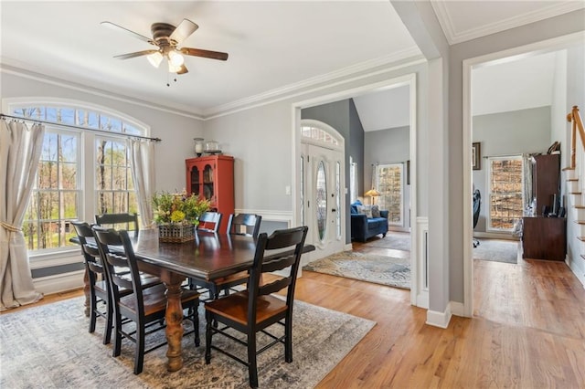 dining room with a ceiling fan, crown molding, light wood-style floors, and baseboards