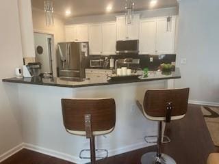 3311 Lindenridge Dr, Buford, GA 30519 - kitchen featuring stainless steel fridge, a peninsula, white cabinets, a breakfast bar, and dark countertops