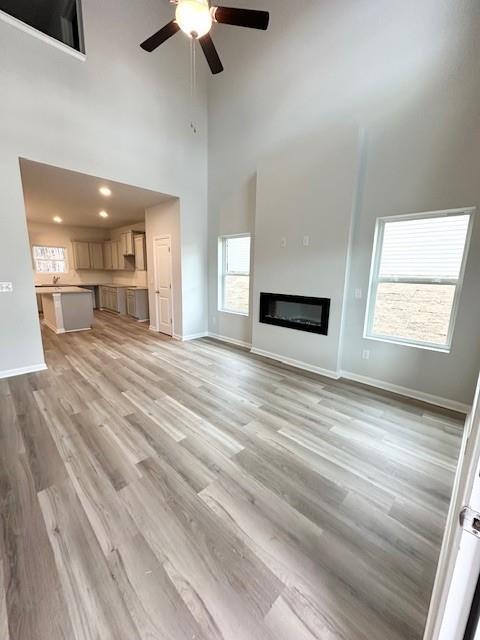 unfurnished living room with a towering ceiling, light hardwood / wood-style flooring, and plenty of natural light