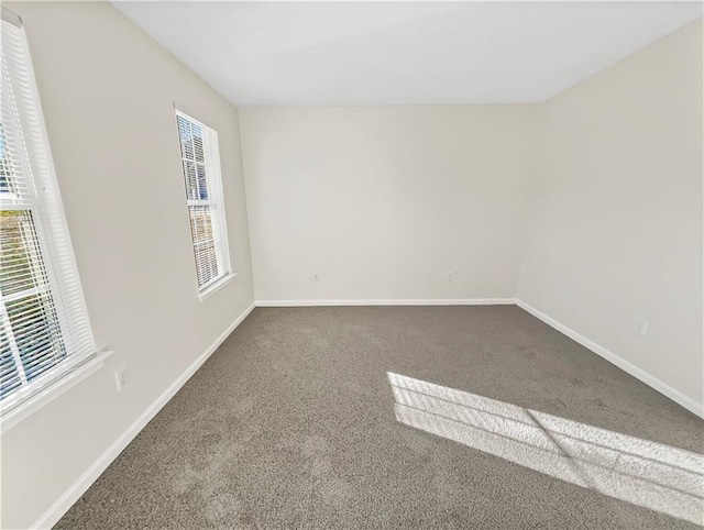 unfurnished room featuring a healthy amount of sunlight, carpet floors, and baseboards