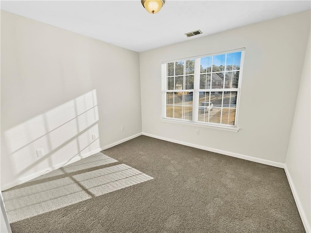 unfurnished room with baseboards, visible vents, and dark carpet