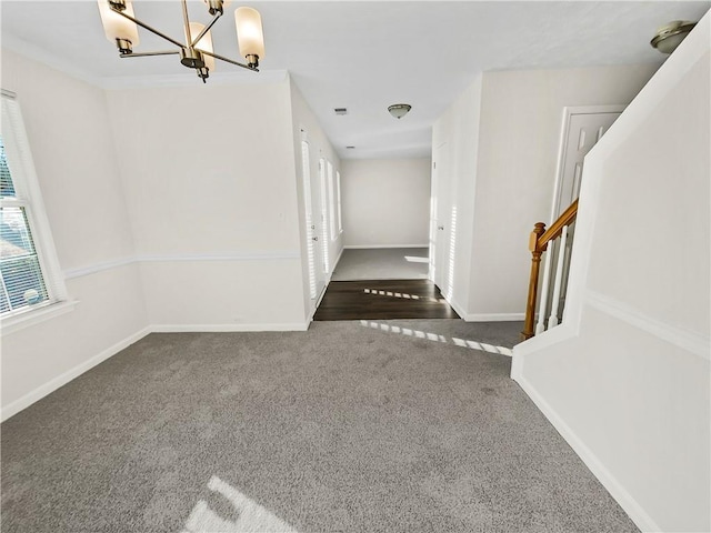 foyer featuring carpet floors, visible vents, a chandelier, baseboards, and stairs