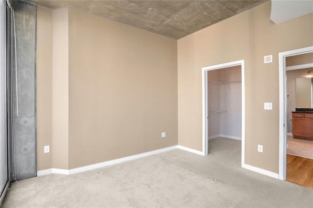 unfurnished bedroom with light carpet, a spacious closet, and a closet