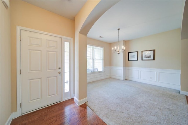 1575 Parkside Village Dr, Cumming, GA 30040 - entrance foyer featuring a chandelier, arched walkways, carpet, a wainscoted wall, and wood finished floors
