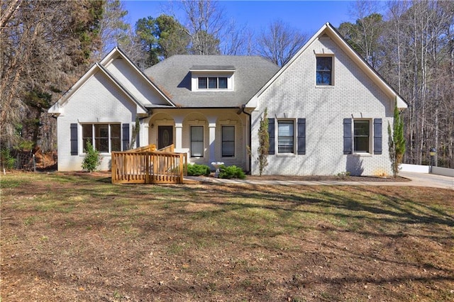 view of front facade with brick siding, covered porch, and a front lawn