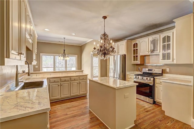 kitchen featuring light wood finished floors, a notable chandelier, appliances with stainless steel finishes, and a sink