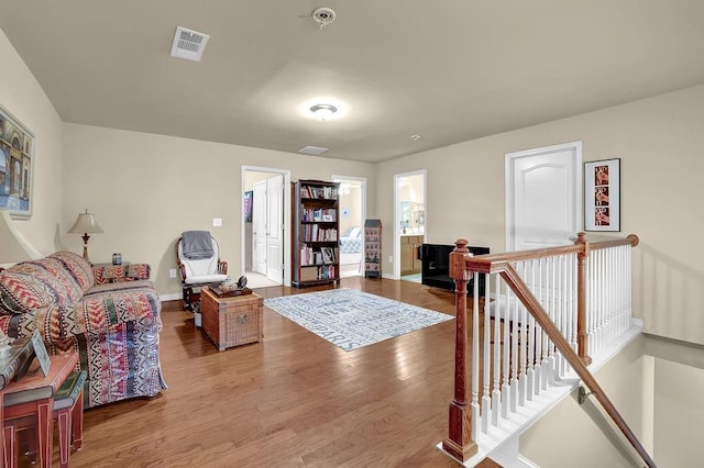 living room with wood finished floors, visible vents, and baseboards