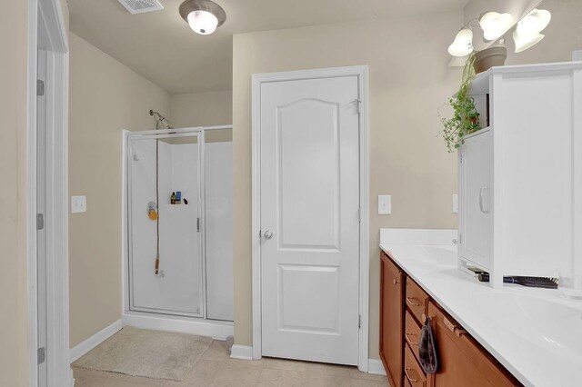 bathroom with vanity, a shower stall, tile patterned flooring, and baseboards