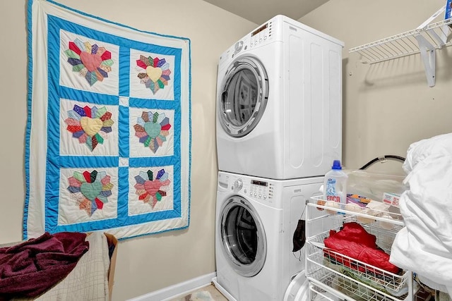 clothes washing area with stacked washer and dryer, laundry area, and baseboards