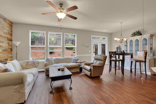 living room featuring wood finished floors, baseboards, visible vents, and ceiling fan with notable chandelier