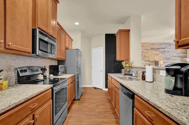 kitchen featuring appliances with stainless steel finishes, tasteful backsplash, light wood finished floors, and a sink