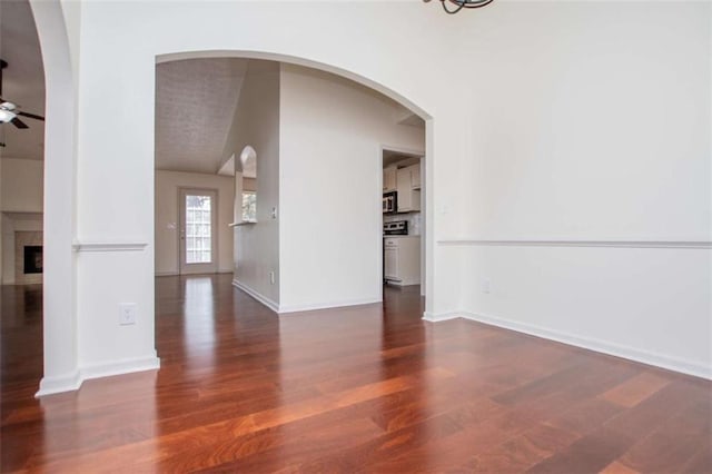 spare room with a fireplace, wood finished floors, baseboards, and ceiling fan