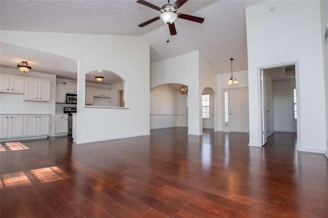 unfurnished living room with baseboards, dark wood finished floors, a textured ceiling, high vaulted ceiling, and a ceiling fan