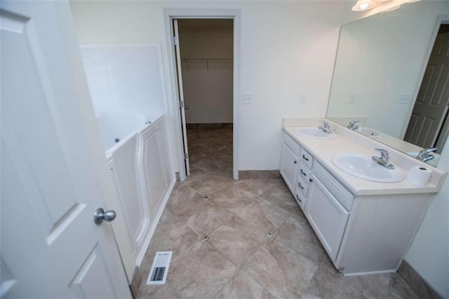 full bath with double vanity, visible vents, a garden tub, and a sink